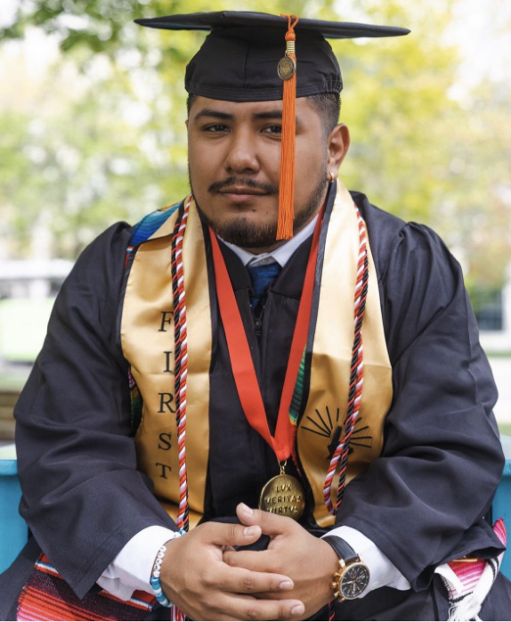 EMERGE Scholar in his cap and gown wearing a First Generation stole